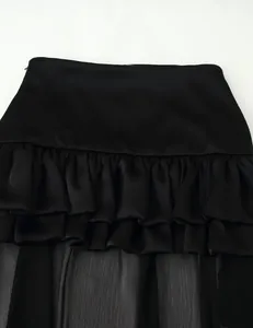 Close-up detail of a black multi-layer ruffled skirt with a long sheer trailing hem