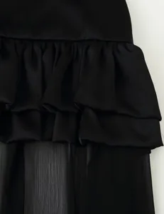 Close-up detail of multi-layered black ruffles and sheer long tail on an elegant maxi skirt