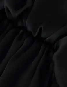 Detailed macro view of the soft black layered ruffle fabric texture on a long skirt