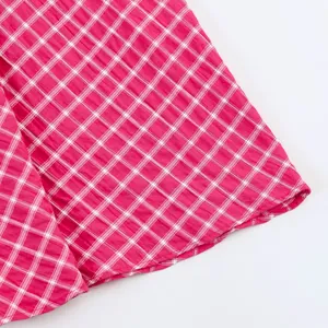 Close-up of pink and white gingham plaid fabric showing fine texture and hem detail.