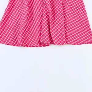 Detail view of a pink and white checkered midi skirt with pleated hemline details