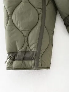 Close-up detail of olive green quilted winter jacket showing drawstring and stitching.