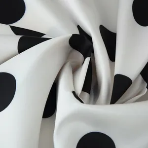 Close-up of elegant white satin fabric with classic black polka dot pattern details