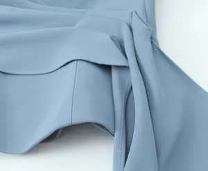Macro detail shot showing elegant light blue pleated fabric texture on fashion top