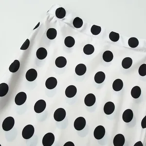 Close-up of elegant white high-waisted skirt with classic black polka dot pattern