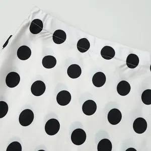 Detailed view of high-waist white skirt with bold black polka dots and fine stitching