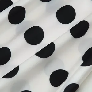 Macro detail of elegant white chiffon fabric with large black polka dots and folds.