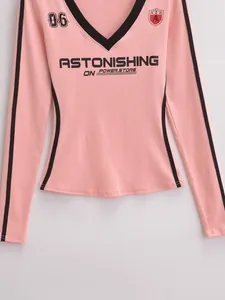 Detail van roze T-shirt met lange mouwen met zwarte V-hals bies en letteropdrukken
