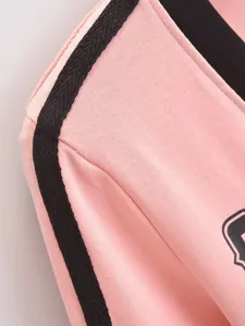 Detailopname van roze T-shirt met V-hals en zwarte contraststreep op de schouder