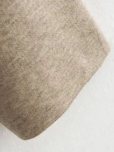 Makroaufnahme der beigen Strickstofftextur mit feinem Fischgrätenmuster für Damenmäntel