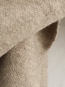 Nahaufnahme der weichen, haferflockenfarbenen Strickstofftextur am kurzen Wintermantel