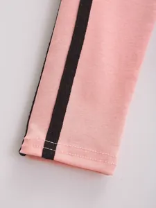 Detailweergave van de roze mouwboord met contrasterende zwarte strepen en stiksels.