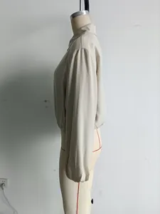 Zijzicht van een stijlvol beige bomberjack met rits en pofmouwen op een paspop.
