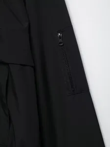 Vista dettagliata della tasca funzionale con zip su una giacca a vento nera impermeabile