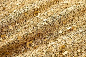 Detailaufnahme von goldenem Tweed-Stoff mit Pailletten und floralen Perlenstickereien