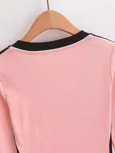 Detail van een roze T-shirt met lange mouwen en een contrasterende zwarte kraag.