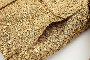 Nahaufnahme der glänzenden goldenen Paillettenverzierungen auf einer Tweed-Jackentasche