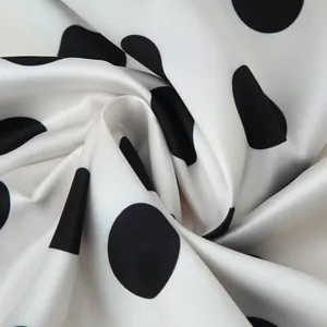 Close-up of white satin fabric with large black polka dots showing smooth texture