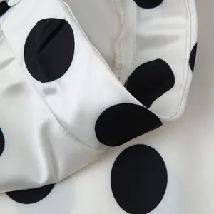 Detailed macro view showing the smooth texture of white satin fabric with black polka dots