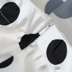 Detailed macro view of the invisible zipper on a white and black polka dot satin skirt