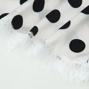Macro detail of elegant white satin fabric with black polka dots and white lace trim