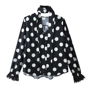 Detail of black polka dot blouse with elegant lace-trimmed cuffs and V-neck tie.