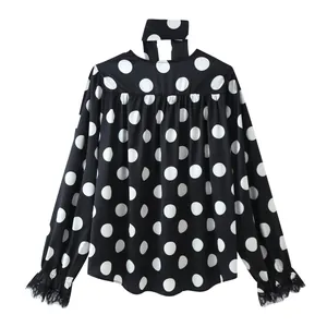 Detailed view of a black polka dot blouse featuring elegant lace cuffs and a tie neck collar