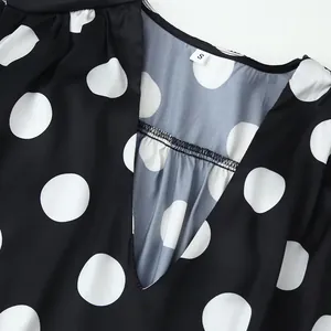 Close-up detail showing the V-neckline and large white polka dots on black fabric