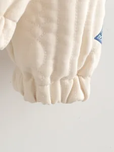 Primo piano del polsino elasticizzato a lanterna su una giacca trapuntata color crema