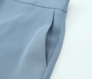 Detail view of light blue high waist trousers featuring side pocket construction