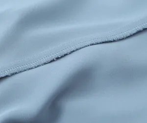 Macro detail view showing high-quality overlock stitching on soft light blue fabric