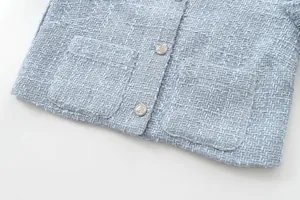 Close-up detail of light blue tweed jacket showcasing rough woven texture and silver buttons