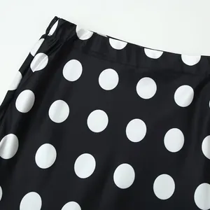 Detail view of a high-waisted black skirt with classic white polka dot pattern.