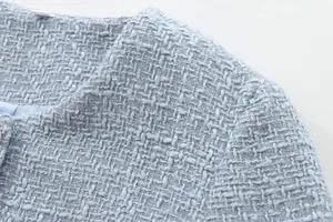 Macro detail view showing the intricate weave of the light blue tweed short jacket fabric.