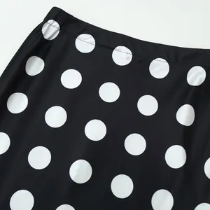 Detail of high-waisted black skirt with white polka dots showing fabric texture