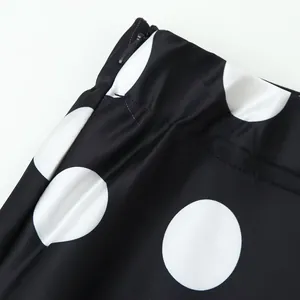 Close-up shot of black and white polka dot fabric with detailed zipper at the waistline