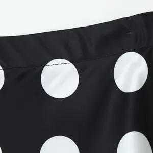 Detailed macro view of white polka dots on black fabric showing waistband stitching detail