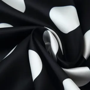 Detailed close-up of elegant black and white polka dot satin fabric with a silky sheen