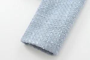 Close-up detail of the premium light blue tweed fabric and sleeve cuff texture