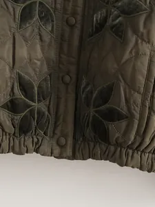 Vista dettagliata della giacca trapuntata verde oliva con eleganti applicazioni floreali.