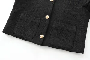 Detailed view of black tweed jacket featuring ornate gold buttons and patch pockets.