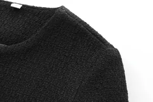 Close-up detail of a premium black tweed jacket showing round neck and texture