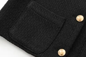 Close-up detail of black tweed jacket featuring elegant gold crest buttons and pocket