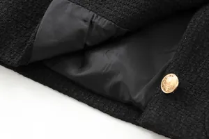 Close-up of black tweed jacket featuring ornate gold button and smooth lining