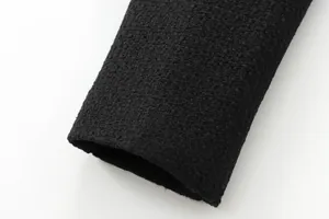 Detailed close-up of black tweed jacket sleeve cuff showing premium bouclé fabric texture