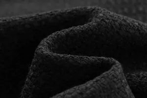 Macro view showing the intricate woven texture and thick yarn of black coarse tweed fabric.