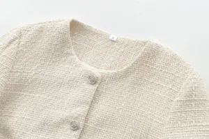 Detailed view of cream tweed jacket neckline with decorative silver buttons and size S tag.