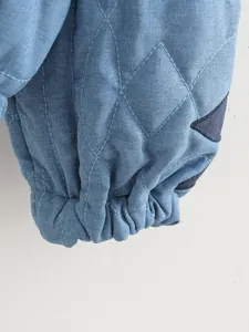 Dettaglio della manica di una giacca trapuntata blu con polsino elastico e toppa a stella
