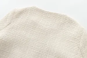 Detailed close-up showing the beige tweed fabric texture of a round neck jacket