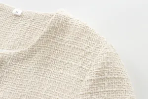 Close-up of elegant cream tweed jacket neckline showing textured weave and size tag.